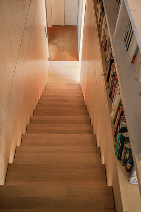 Wooden staircase with built-in bookshelves along the side wall.