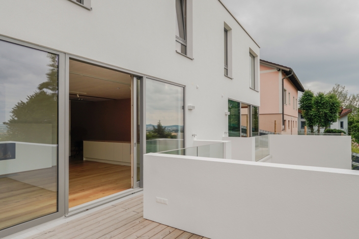 Terrasse mit Glasgeländer und offener Wohnbereich