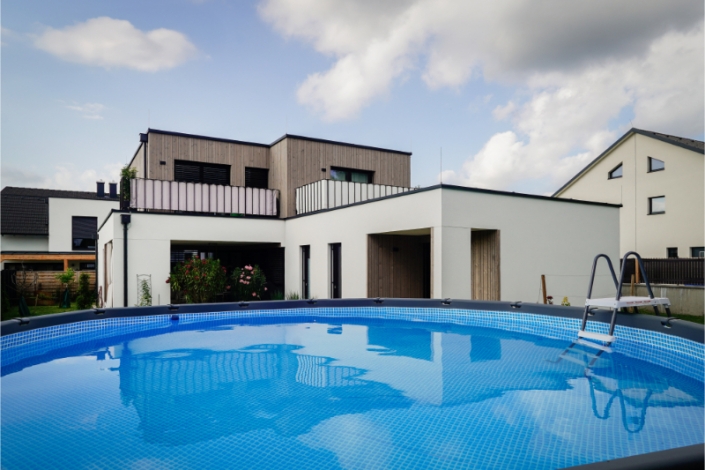 Modern white house with balcony and swimming pool in the garden.