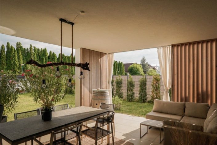 Covered outdoor dining area with table, chairs, and hanging light.