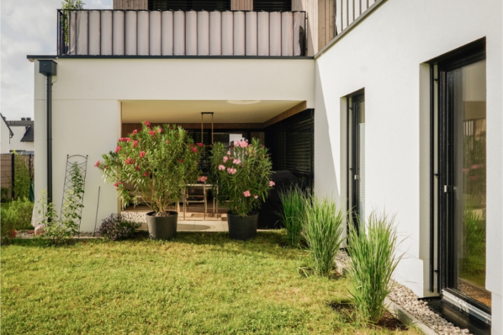 Contemporary house with balcony and garden plants in front.