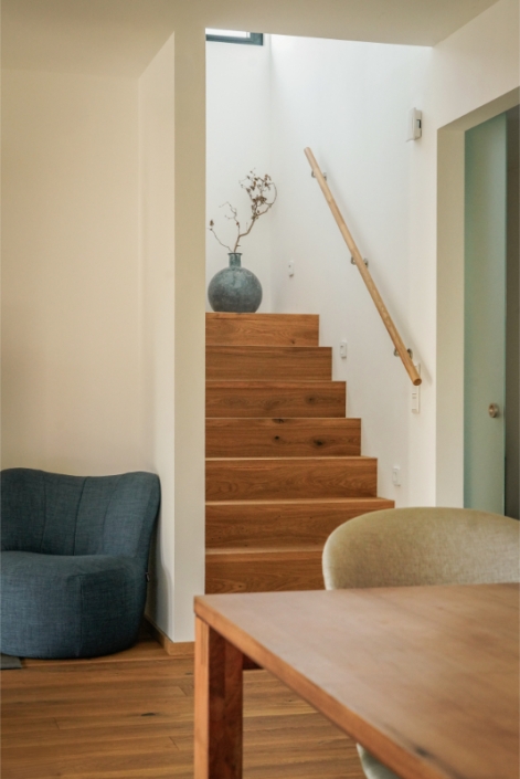 Wooden staircase with handrail, next to a small armchair and table.