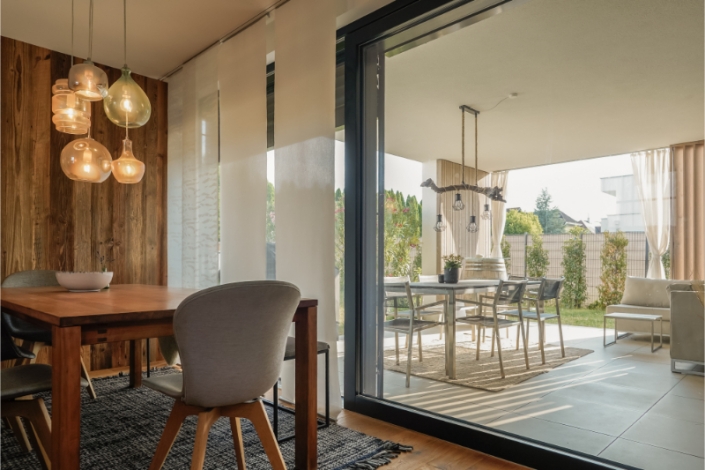 Dining room with wooden table, chairs, and modern hanging lights.
