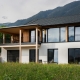 Contemporary house exterior with balcony and large windows, surrounded by nature.