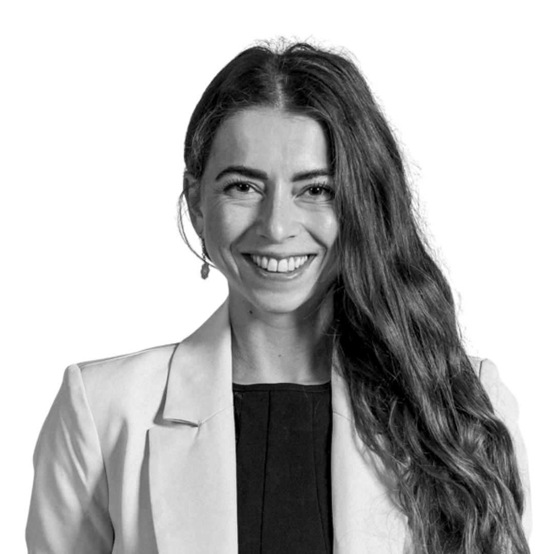 Smiling woman with long hair wearing a blazer, photographed against a white background.